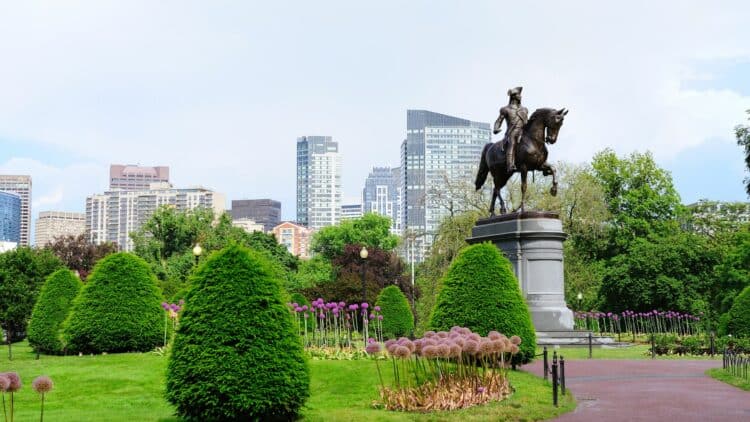 Statue équestre au cœur d’un parc paysager de Boston avec les immeubles modernes en arrière-plan.
