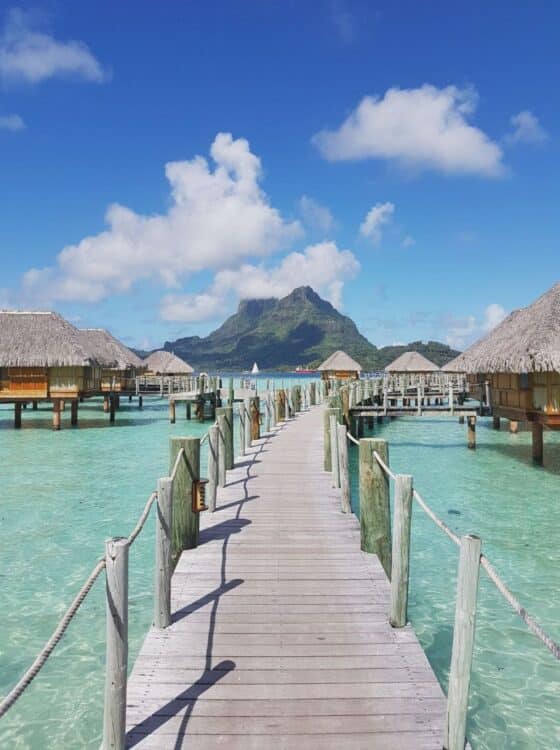 Bungalows sur pilotis dans un lagon turquoise en Polynésie française.