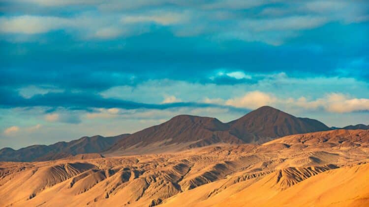 Reliefs désertiques et montagnes sous un ciel nuageux dans le désert d’Atacama.