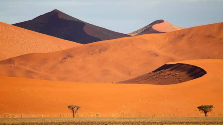 Grandes dunes rouges du désert du Namib sous un ciel dégagé en Namibie.