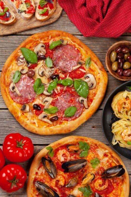 Spécialités de la gastronomie italienne avec pizzas, pâtes, olives et ingrédients méditerranéens.