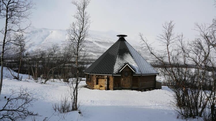 Kota traditionnel en bois dans un paysage enneigé près d’Abisko, en Laponie suédoise.