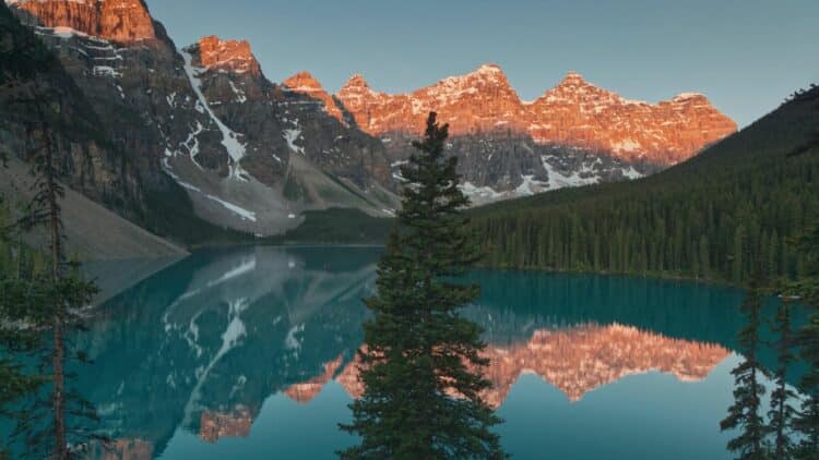 Reflets des montagnes illuminées au coucher du soleil sur le lac Moraine.