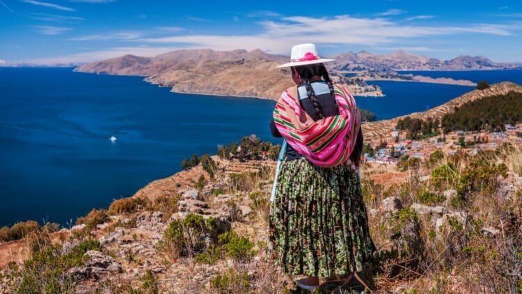 Habitante bolivienne face au lac Titicaca et à ses paysages andins.