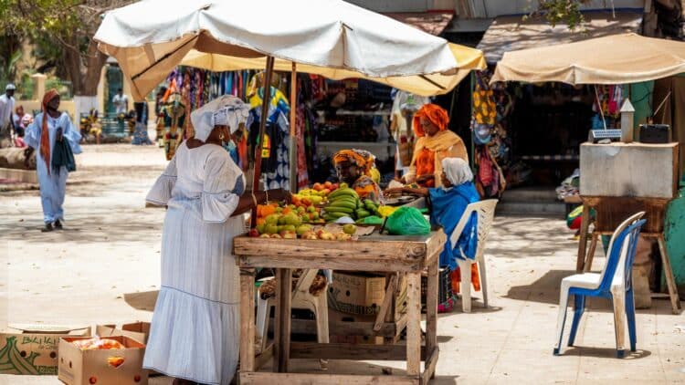 Scène de marché local avec étals de fruits au Sénégal.