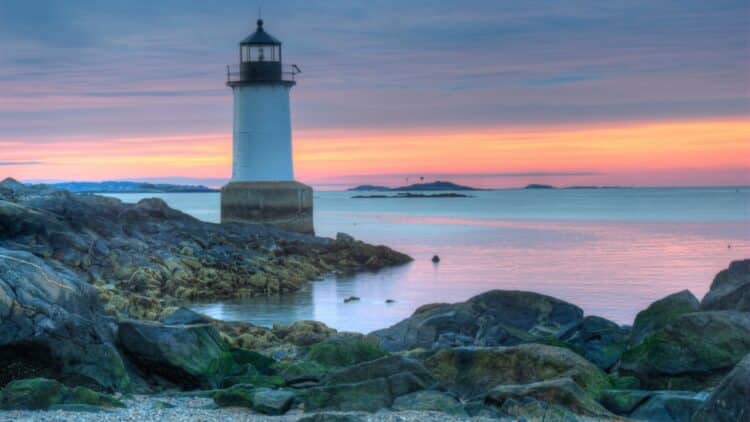 Phare blanc sur la côte rocheuse du Massachusetts au coucher du soleil.