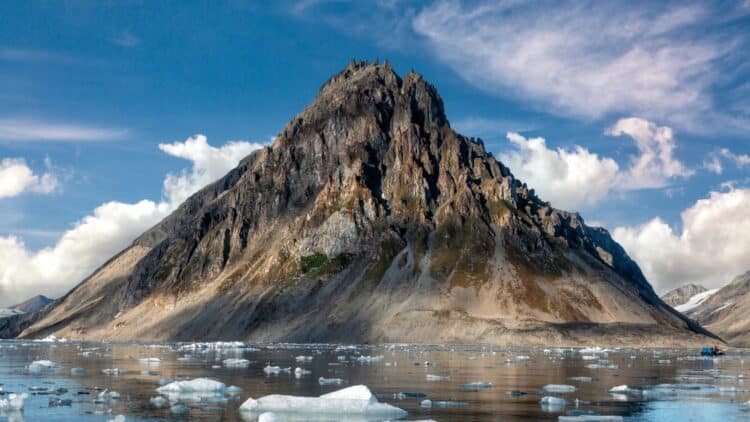 Montagne rocheuse dominant un fjord parsemé d'icebergs au Svalbard.