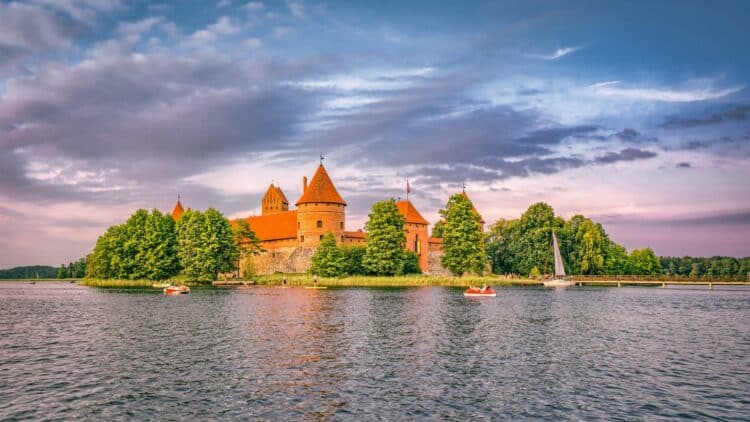 Château de Trakai entouré par un lac en Lituanie au coucher du soleil.