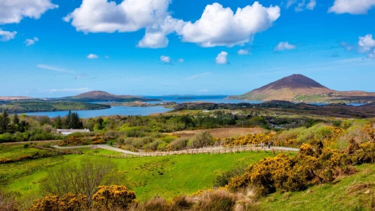 Collines verdoyantes, lacs et reliefs du Connemara sous un ciel bleu, en Irlande.