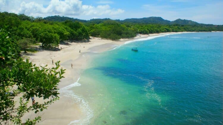Plage de sable clair bordée par la végétation tropicale sur la côte Pacifique du Costa Rica.