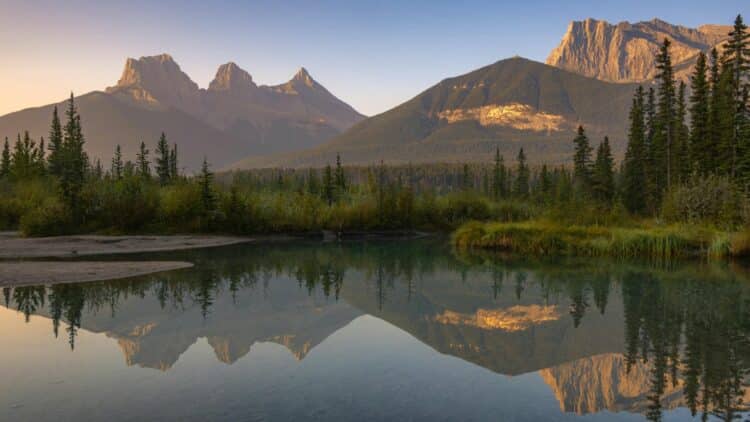 Reflets des montagnes Rocheuses dans une rivière calme en Alberta.
