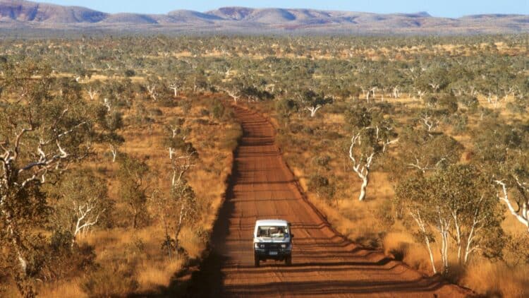 Véhicule circulant sur une piste rouge au cœur de l’Outback australien.