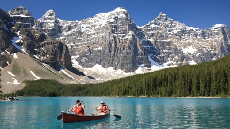 Lac turquoise au pied des sommets enneigés des Rocheuses canadiennes.