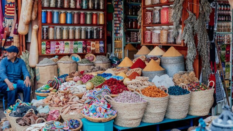 Étal coloré d’épices, de fleurs séchées et d’artisanat dans un souk marocain.