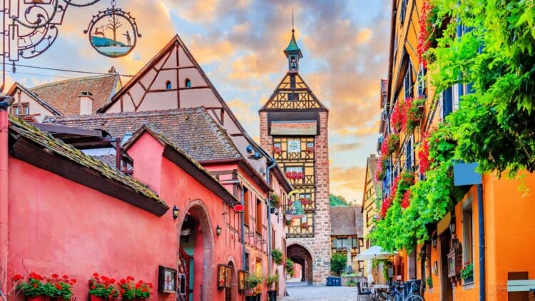 Village traditionnel d'Alsace avec maisons à colombages fleuries.
