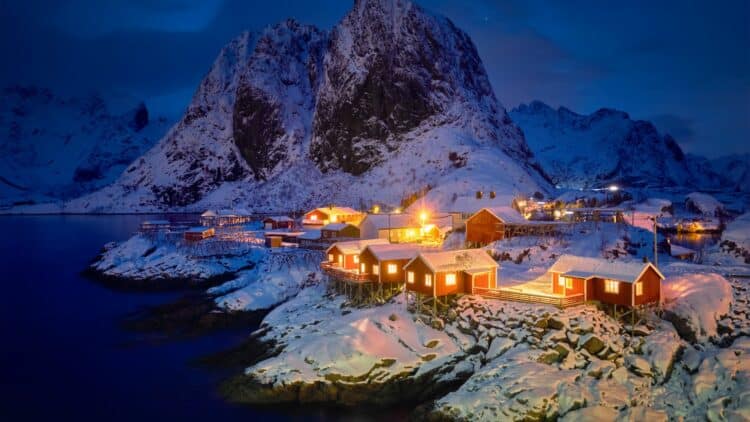 Village de pêcheurs enneigé dans les îles Lofoten, en Norvège, à la tombée de la nuit.
