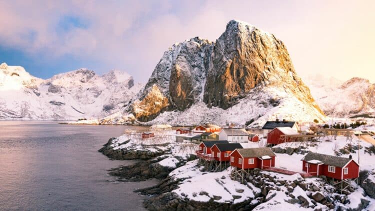 Maisons rouges enneigées au bord d’un fjord dans les îles Lofoten, en Norvège.