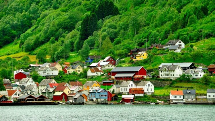 Petit village traditionnel au bord du Sognefjord, entouré de collines verdoyantes, en Norvège.