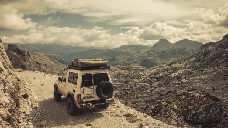 4x4 sur une piste rocheuse au milieu d'un massif montagneux.