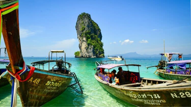 Bateaux traditionnels long-tail sur une plage en Thaïlande.