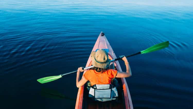 Personne faisant du canoë sur un lac calme au cœur d'une nature préservée.