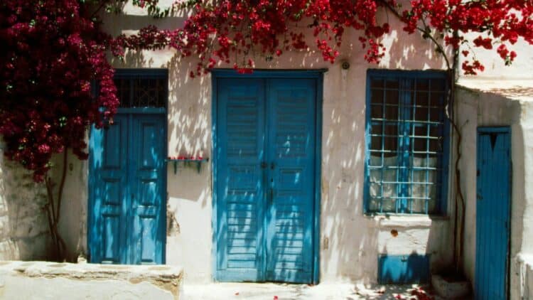 Maison traditionnelle aux volets bleus et bougainvilliers à Corfou.