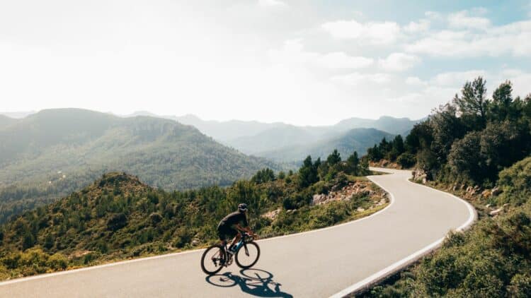 Cycliste sur une route de montagne offrant une vue panoramique.