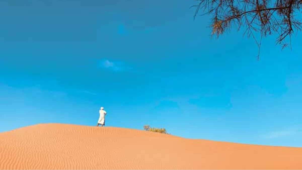 Silhouette marchant sur une dune de sable dans le désert marocain.