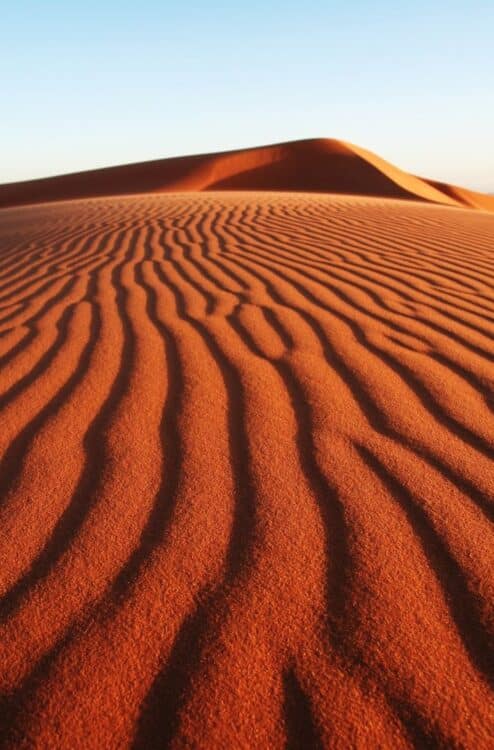 Dunes de sable orangé du Sahara marocain façonnées par le vent.