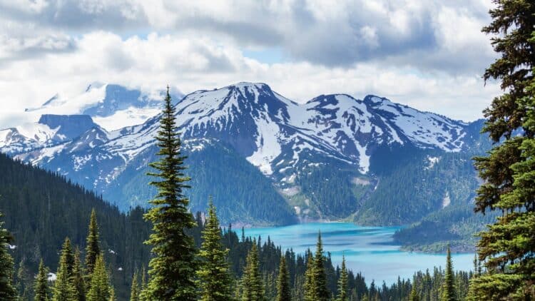 Lac turquoise entouré de montagnes enneigées dans les Rocheuses canadiennes.