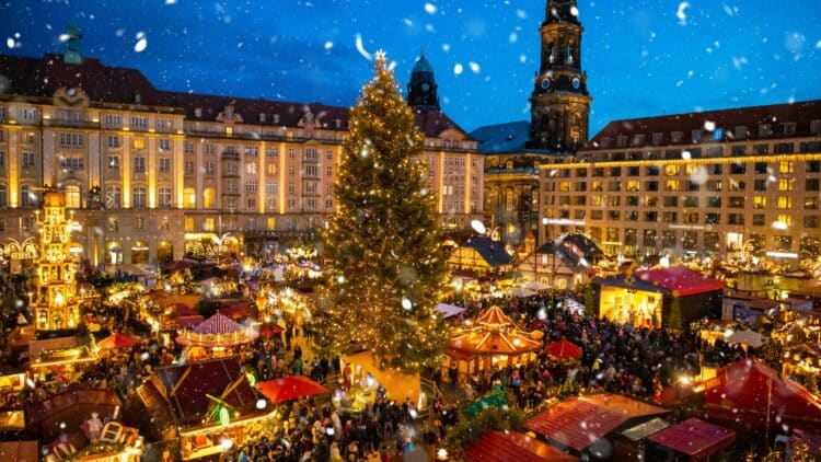 Grand marché de Noël illuminé en Allemagne avec un sapin géant sous la neige.