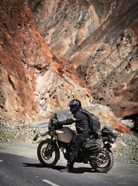 Motard faisant une pause sur une route traversant un canyon rocheux.