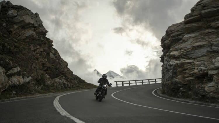 Motard empruntant une route de montagne aux virages spectaculaires.