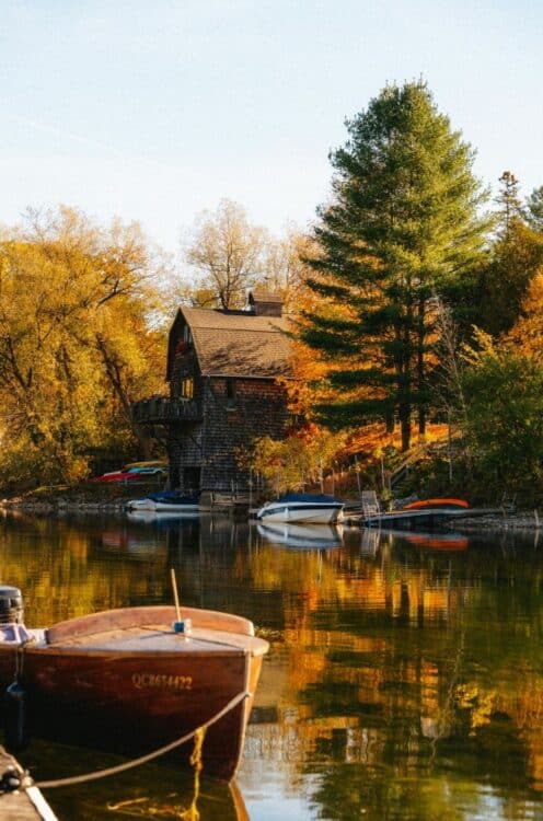 Chalet au bord d'un lac entouré de forêts aux couleurs de l'automne au Canada.