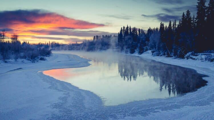 Rivière partiellement gelée au coucher du soleil dans les paysages sauvages d'Alaska.