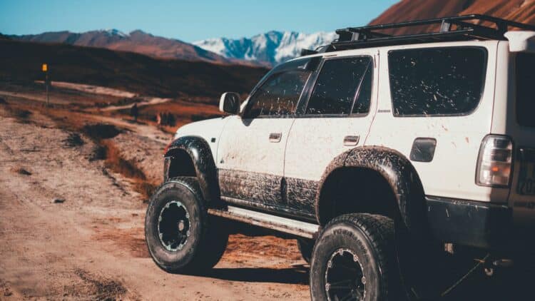 Véhicule 4x4 sur une piste de terre avec des montagnes en arrière-plan.