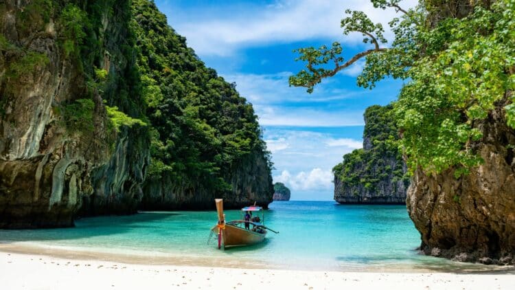 Bateau traditionnel long-tail sur une plage paradisiaque en Thaïlande.