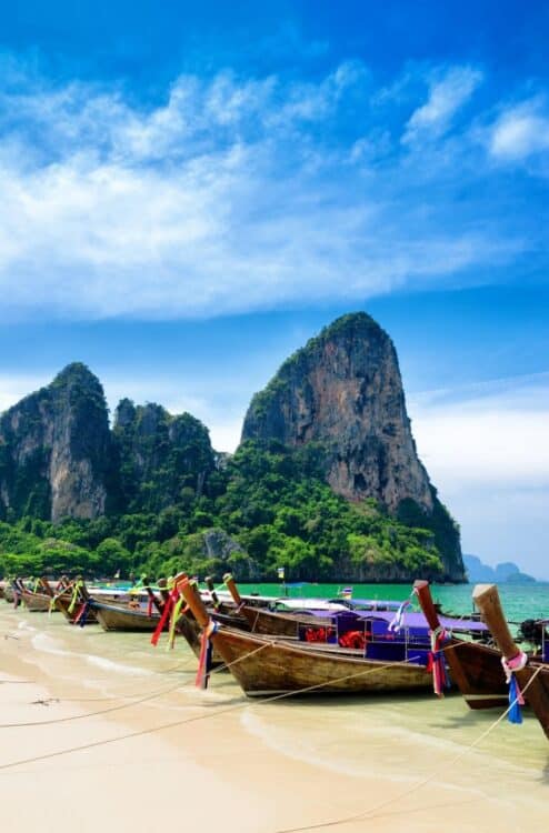 Bateaux traditionnels long-tail amarrés sur une plage paradisiaque en Thaïlande.