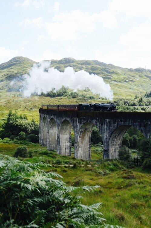 Train à vapeur traversant un viaduc au cœur des paysages d'Écosse.