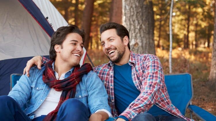 Couple d'hommes partageant un moment de complicité lors d'un séjour en pleine nature.